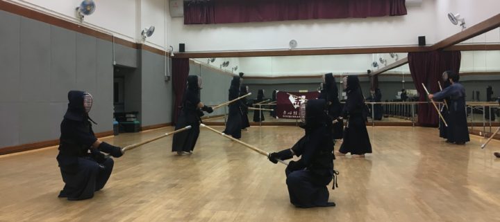 Photo of a practice room with numerous people in kendo gear.