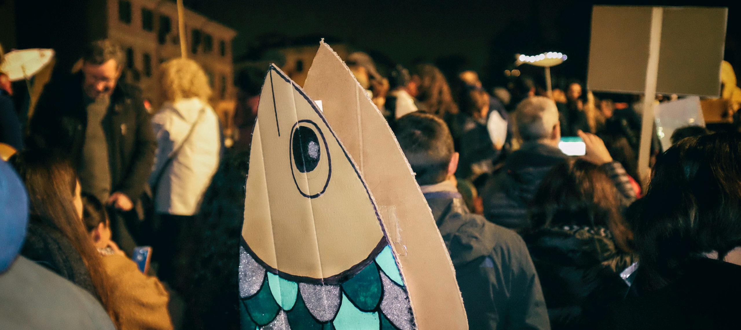 Photograph of protestors holding up sardine-shaped signs at a flash mob in Verona, Italy.