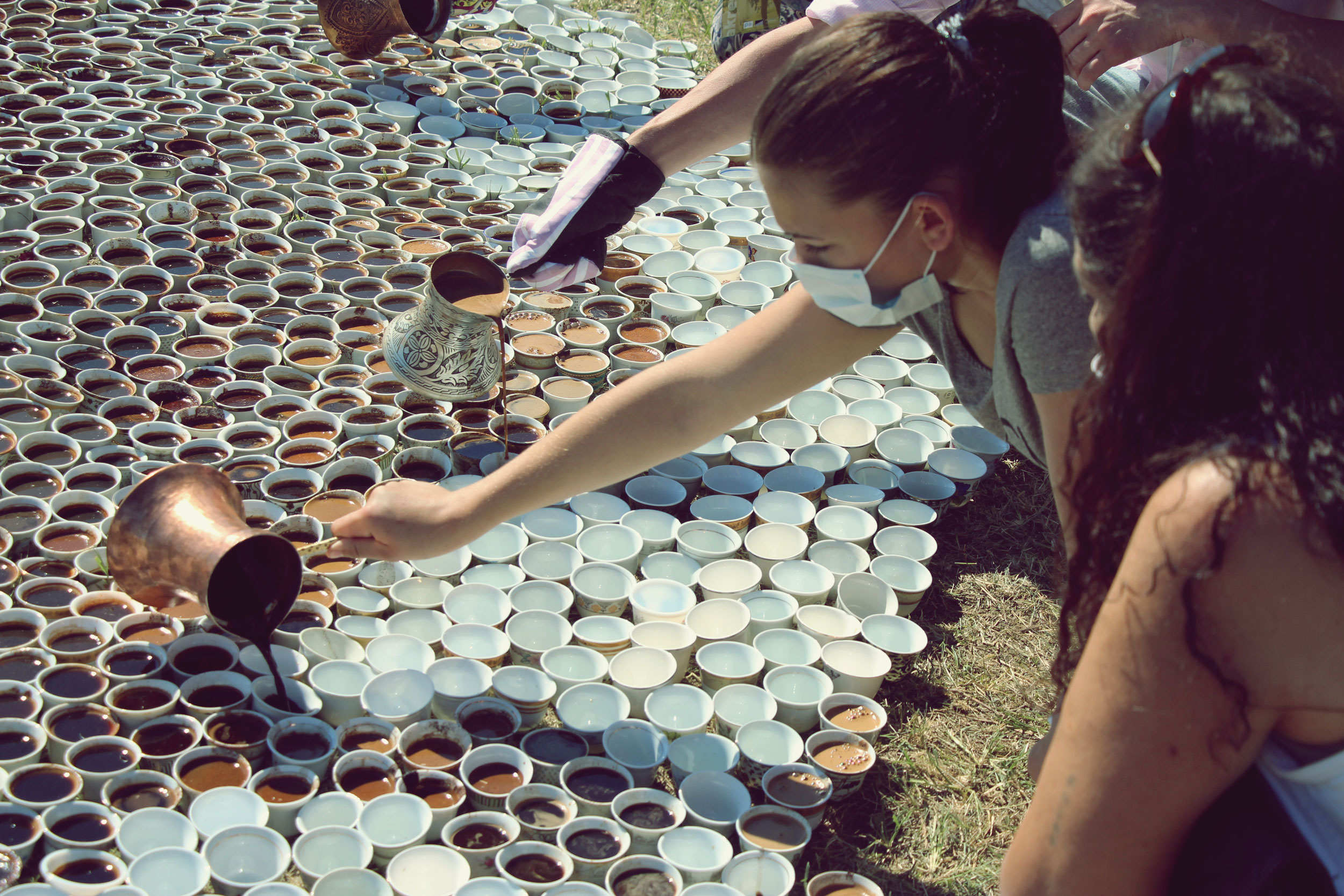 A photograph of people pouring liquid into cups.
