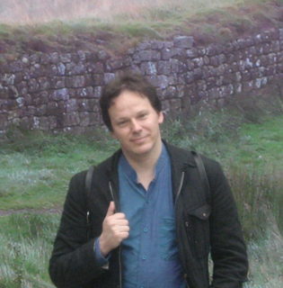 Photograph of a man standing in front of a wall
